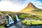 Kirkjufell Waterfalls and Mountain at sunset, wide angle view on a sunny summer day