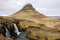 Kirkjufellsfoss waterfall, Kirkjufell mountain, raincloud, hayfield, Iceland