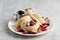 Kiseki Pancake with Fresh Fruits banana, strawberry, raspberry and Maple Butter Cream in white plate on grey background