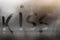Kiss inscription painted on sweaty glass on rainy autumn day, Condensation and steam on window in cold autumn weather with