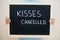 Kisses cancelled. Coronavirus concept. Boy hold inscription on the board