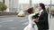 kissing honeymooners in big city, bride and groom are embracing on street