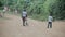 Kisumu,Kenya - May 17, 2018: Back view of boys walking through the road in Africa. Male with bicycle walking in forest.