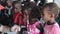 KISUMU,KENYA - MAY 19, 2018: Caucasian man treating african girls with syrup. Children opening mouth and drink medicine.