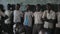 KISUMU,KENYA - MAY 21, 2018: Group of bald African guys stands near wall in the school and looks straight. Boys smiling.