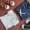 Kit of clothes for infant baby boy. Pants, shirt and tiny shoes on brown background. Flat lay design. Baby`s goods concept.