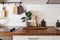 Kitchen brass utensils, chef accessories. Hanging kitchen with white tiles wall and wood tabletop.Green plant on kitchen