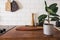 Kitchen brass utensils, chef accessories. Hanging kitchen with white tiles wall and wood tabletop.Green plant on kitchen