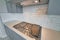 Kitchen with cooktop stove and exhaust hood against white tile backsplash wall