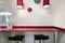 Kitchen of a coworking office with a red countertop and white cabinets, stainless steel stools with black upholstered seats and a