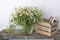 Kitchen decoration. A vase with wild-growing daisies on shabby bench and a box for storing utensils with books