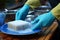 Kitchen duty closeup Hand in blue gloves uses a sponge for dish cleaning