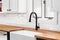 A kitchen faucet detail with a butcher block countertop and subway tile backsplash.