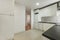 kitchen furnished with white wooden furniture with smooth doors with metal handles, black countertops and white appliances