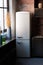 Kitchen interior in dark textured colors with white modern retro fridge, rustic brick wall, window and vase decor