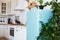 Kitchen interior in white textured colors with blue modern retro fridge and rustic brick wall