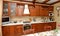 Kitchen interior with wooden furniture and many utensils in warm tones on wide angle view