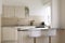 Kitchen with island with two white stools and a gray worktop