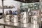 kitchen pots, grater, bowls, saucepans stacked up on a shelf in a kitchen; restaurant / commercial or home kitchen. Brick wall in