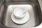 Kitchen sink with clean white plate, bowl and ceramic spoon