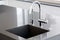 Kitchen sink of dark gray stone with chrome faucet.