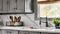 A kitchen sink detail shot with grey cabinets, a white marble countertop and backsplash, and decorations.