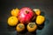 Kitchen still-life. Wholesome ripe fruits of pomegranate, mandarine and persimmon on a dark brown table.