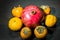 Kitchen still-life. Wholesome ripe fruits of pomegranate, mandarine and persimmon on a dark brown table.