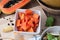 Kitchen table with sliced fresh papaya fruit on wood cutting boa