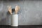 Kitchen tools, wooden Cutlery and metal in a ceramic pot against a grey marble texture wall.