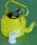 Kitchen utensils and cutlery in old fashioned green vintage teapot in bucket on table along with pepper shaker. Vintage Whistling