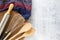 Kitchen utensils, whisk, wooden spoon and rolling pin with traditional cloth on cement background