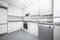 Kitchen with walls lined with white wood cabinets, gray granite countertops,
