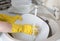 Kitchen washing plates with yellow gloves