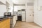 Kitchen with white cabinets, black countertop, chestnut wood flooring