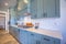 Kitchen with white counter top and bluish gray cabinets against tile backsplash