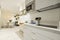 Kitchen with white stone countertops, gloss gray wood cabinets, light