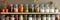 A kitchen white wall with shelves topped with lots of bottles, bowls and jars with spices and products