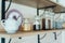 Kitchen wooden shelf with glass jars with coffee and tea leaves and accessories, blue sugar bowl with spoon. Cozy interior in a