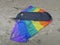 Kite in rainbowcolors with black threads laying on the beach of Velsen Netherlands
