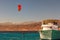 Kiteboarder enjoying surfing in blue water near the moored yacht. Travel and tourism concept