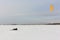 Kiteboarder with orange kite lying in the snow , Ob reservoir, Novosibirsk, Russia
