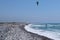 A kiteboarder is pulled across water by a power kite near coast at beautiful blue sky. Man used power of the wind. Extreme sport.