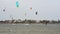 Kiteboarders harness wind power, glide on waves, stormy sea backdrop. Extreme sports enthusiasts perform aerial tricks