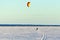 A kiter on skis under a colored dome rides on the big Onega Lake on a hard snow crust.