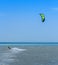 Kitesurfer with green parachute on the blue sea