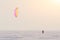 Kitesurfer ride the parachute in the wind among the snow in winter before sunset.