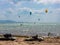 Kitesurfers preparing kiteboards at the beach. Other kiteboarders compete in jumping and stunts and fly after the wind on their