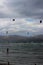 Kitesurfers ride the waves on the beach of Playa de Alcudia against a gray overcast sky . Alcudia.