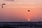 Kitesurfing jump, man kite surfer jumping at sunset golden hour silhouette on orange background